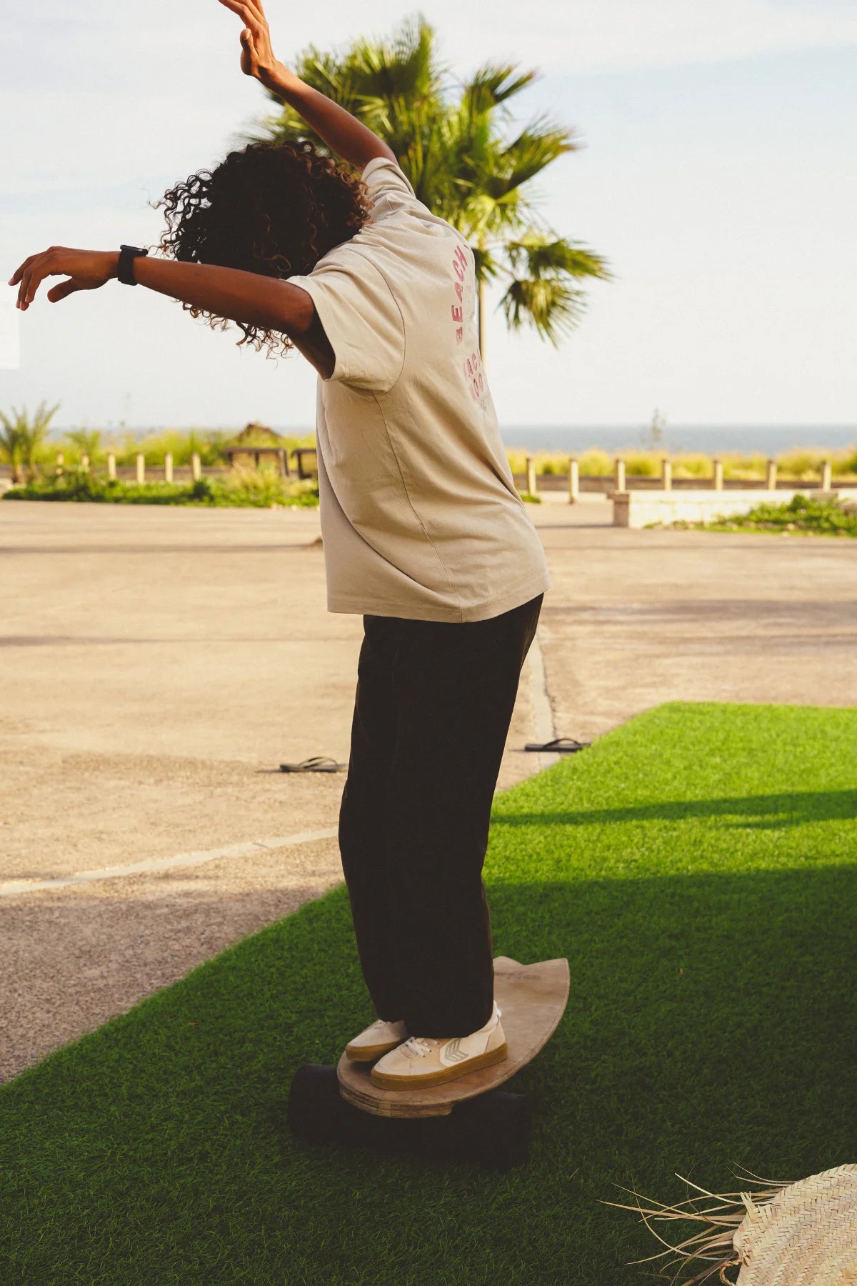 Skateboarder balanciert auf Holzbrett im The Sunkissed Rebels T-Shirt in Sand