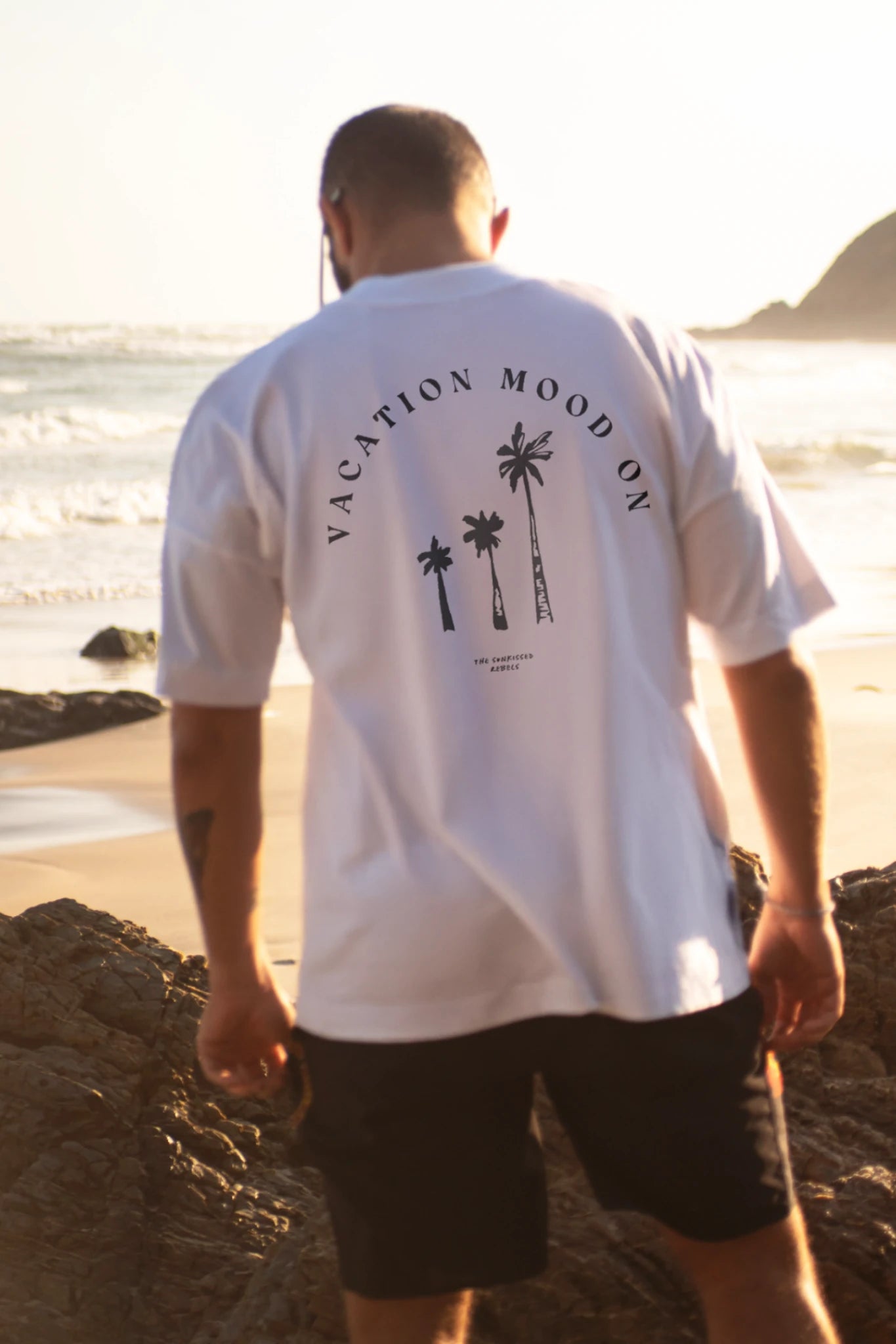 Rückenansicht des Oversized T-Shirt Vacation Mood On White von The Sunkissed Rebels mit Backprint am Strand