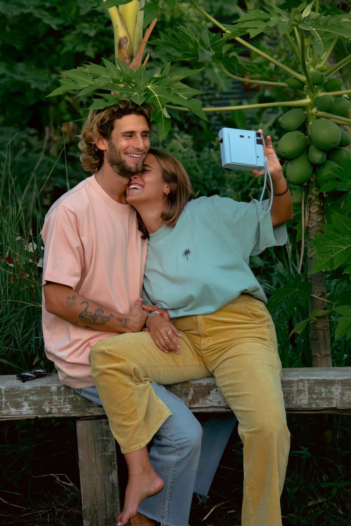 Paar macht Selfie mit Polaroidkamera in oversized T-Shirts von The Sunkissed Rebels