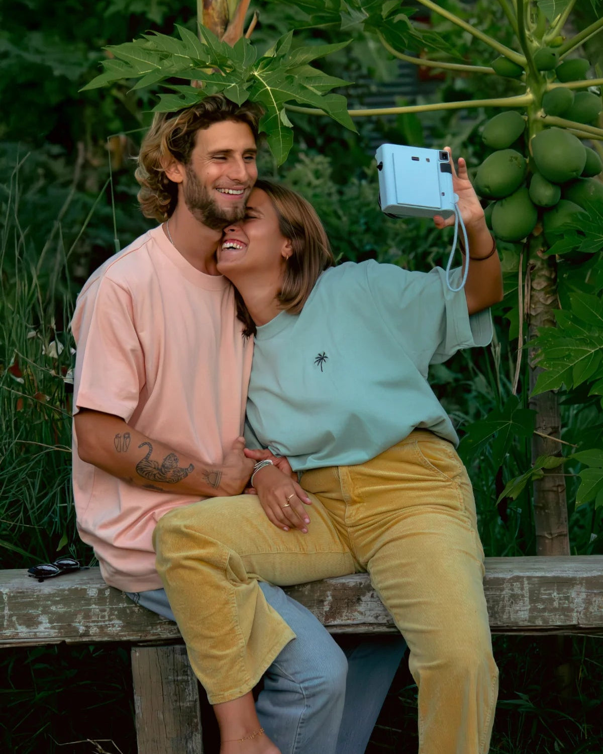 Paar macht Selfie mit Polaroidkamera in oversized T-Shirts von The Sunkissed Rebels