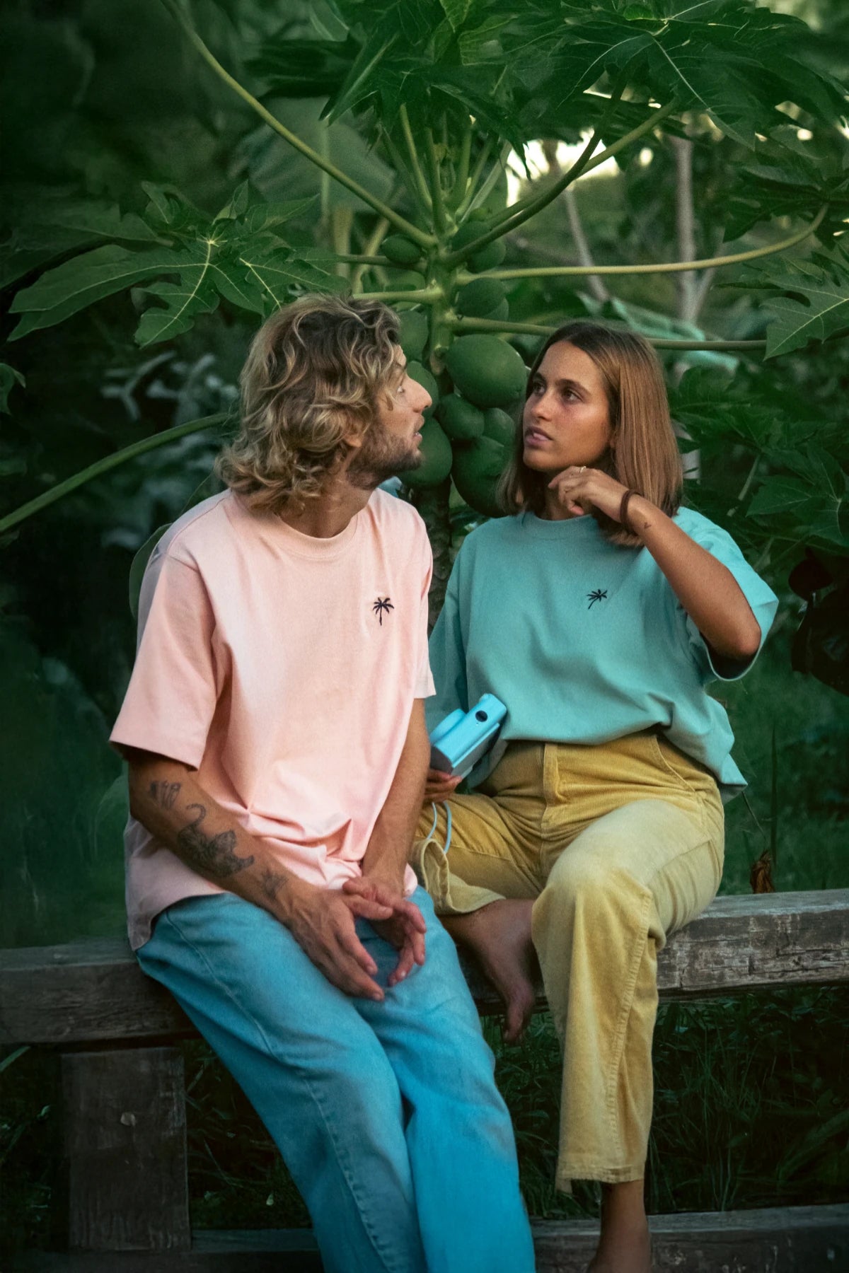 Paarshooting im tropischen Garten mit mintgrünem und apricotfarbenem T-Shirt von The Sunkissed Rebels