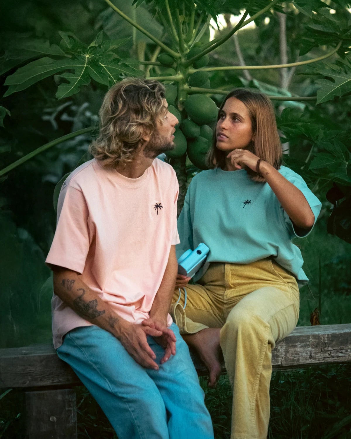 Paarshooting im tropischen Garten mit mintgrünem und apricotfarbenem T-Shirt von The Sunkissed Rebels