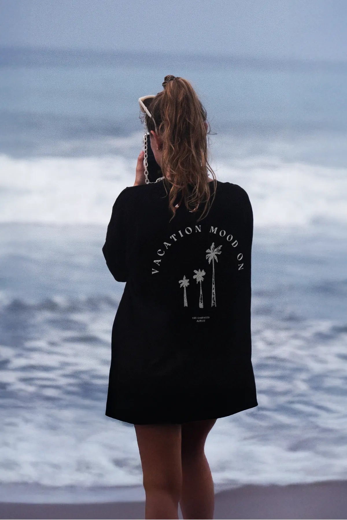 Schwarzes Oversized T-Shirt – Frau mit Sonnenbrille am Ozean