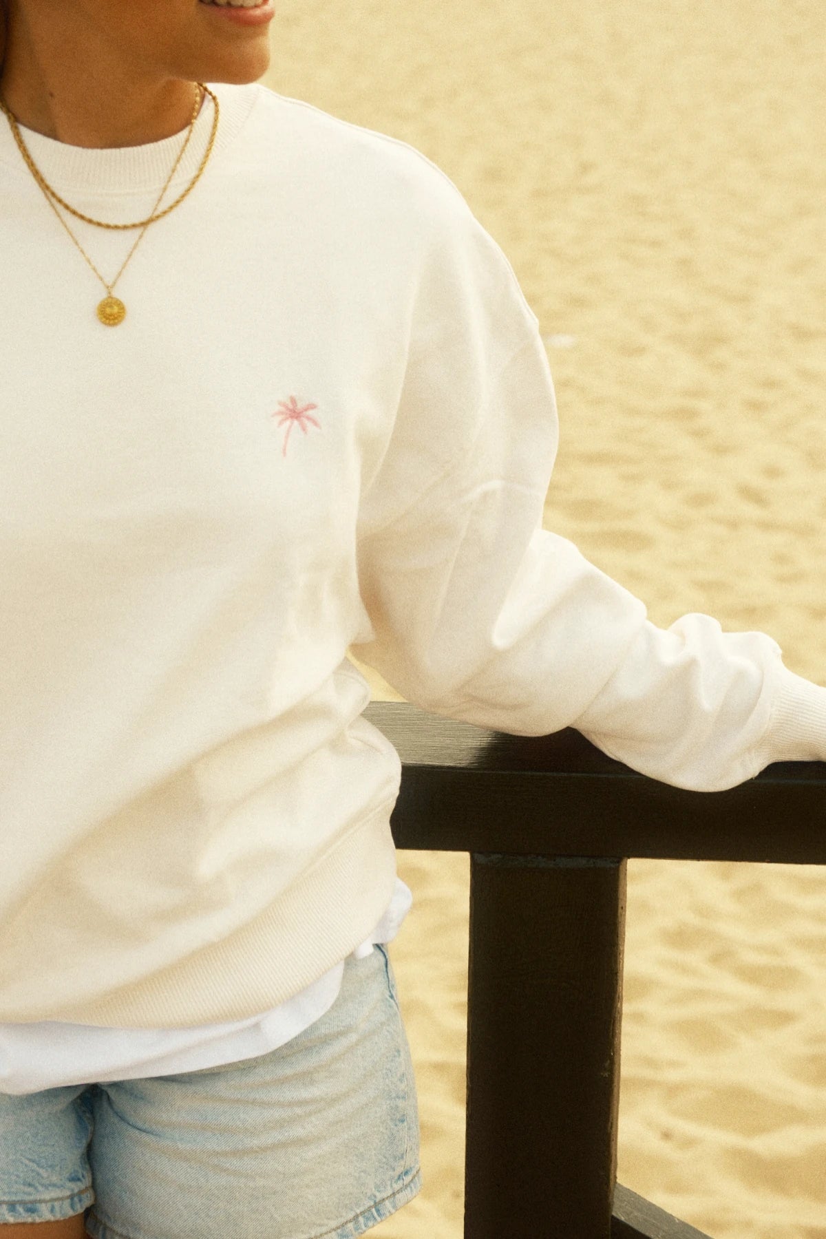 Nahaufnahme vom Palm Tree Sweater – Cream mit pinker Palmenstickerei.