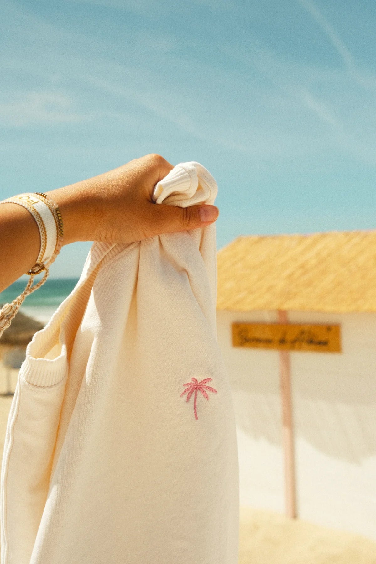 Detailaufnahme der pinken Palmen-Stickerei auf dem Palm Tree Sweater Cream