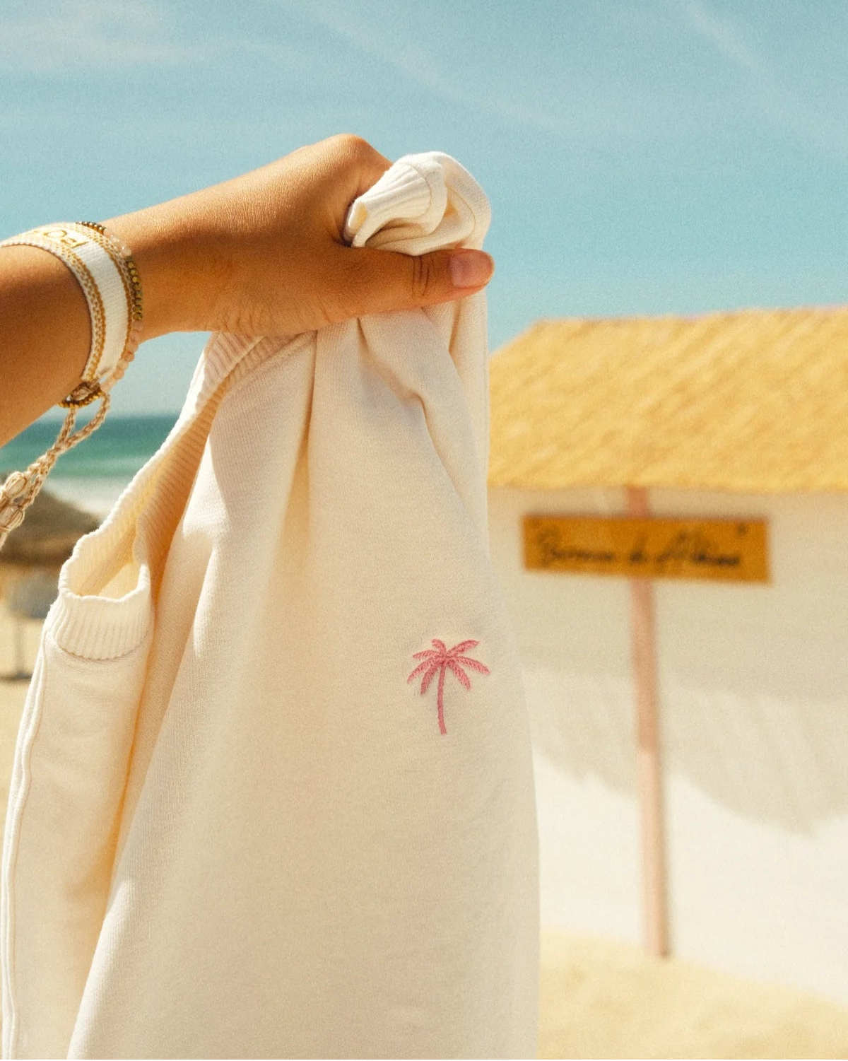 Detailaufnahme der pinken Palmen-Stickerei auf dem Palm Tree Sweater Cream
