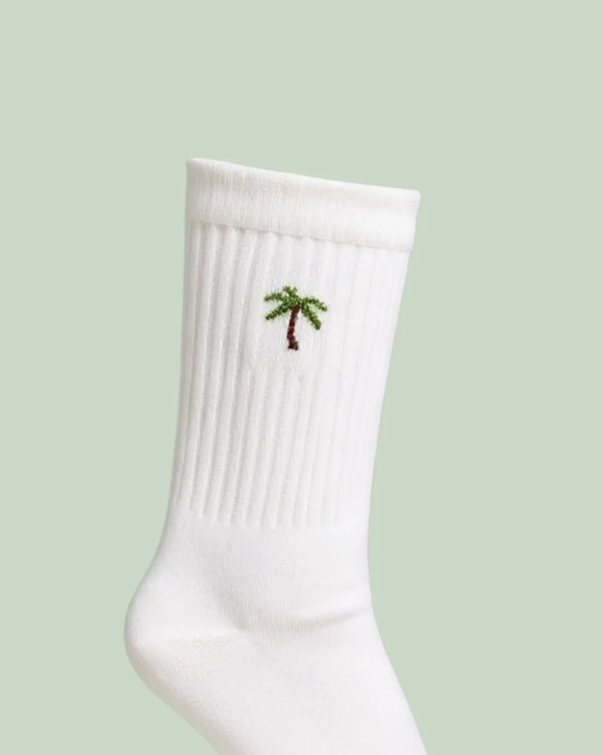 Detailaufnahme der weißen Tennissocken mit Palmenstickerei am gerippten Schaft.
