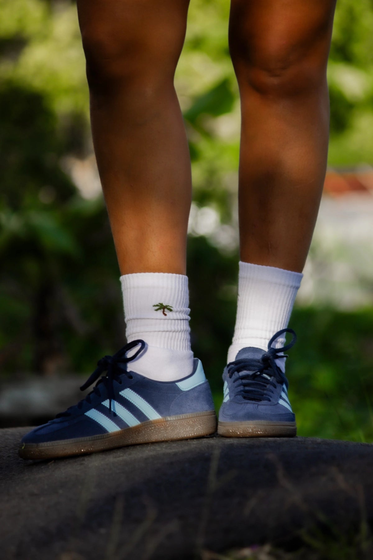 Weiße Palm Tree Tennissocken mit verspieltem Palmenstick beim Beinwurf im tropischen Hintergrund