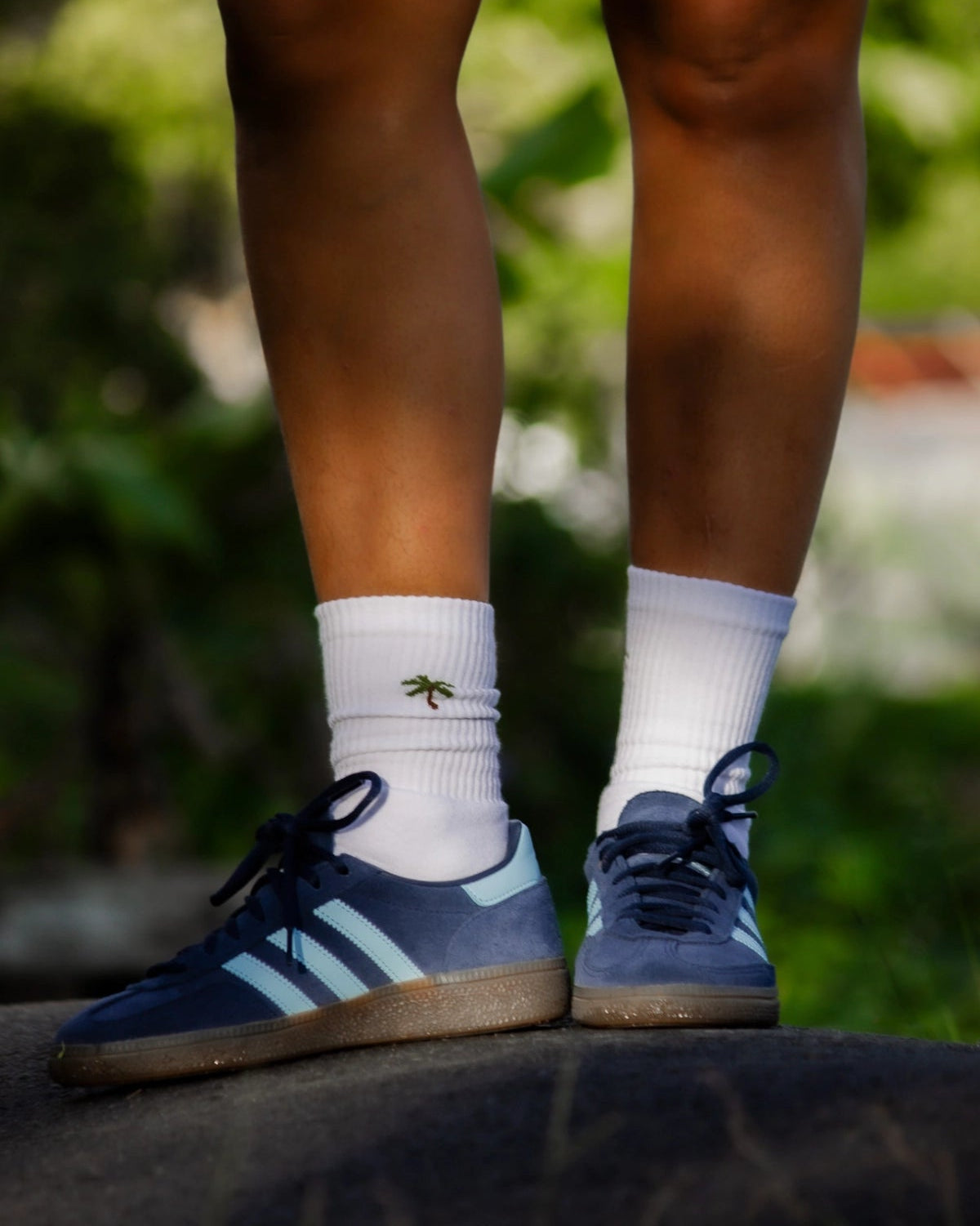 Weiße Palm Tree Tennissocken mit verspieltem Palmenstick beim Beinwurf im tropischen Hintergrund