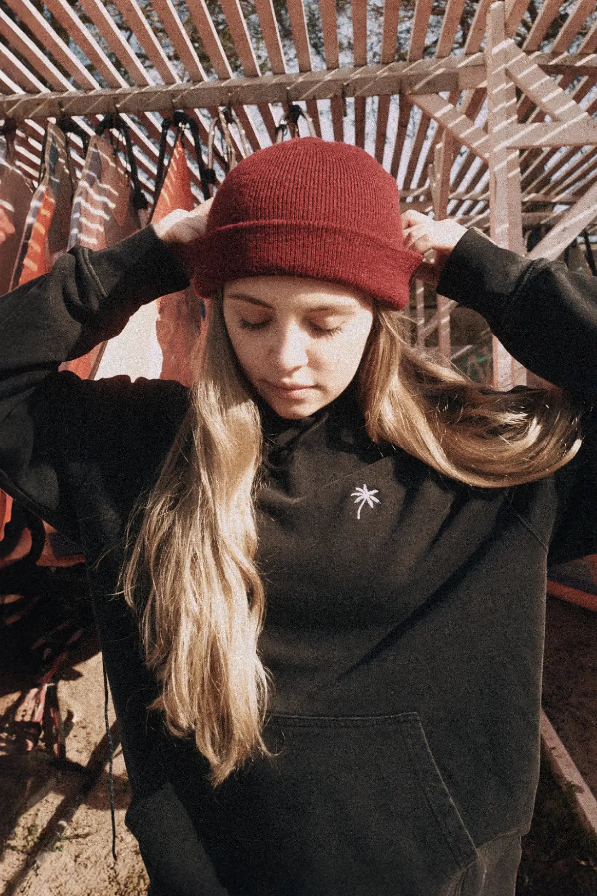 Model von The Sunkissed Rebels trägt den Palm Tree Vintage Hoodie Black im Outdoor-Setting am Strand