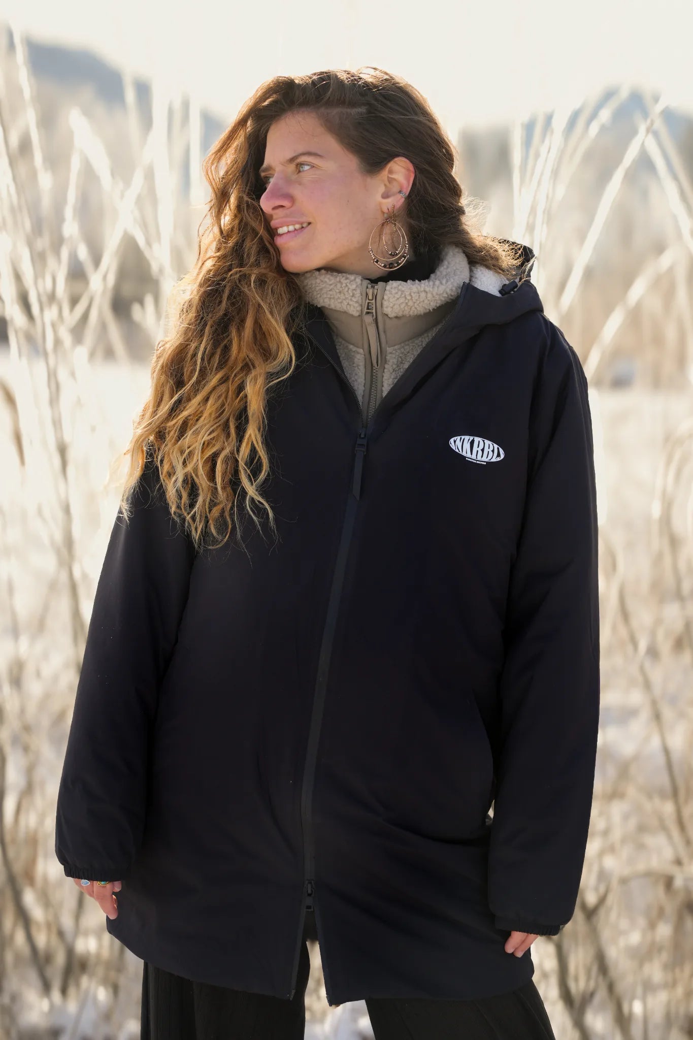 Frau trägt schwarze Rebels Waterproof Sherpa Jacke von The Sunkissed Rebels im Winter Outdoor Portrait