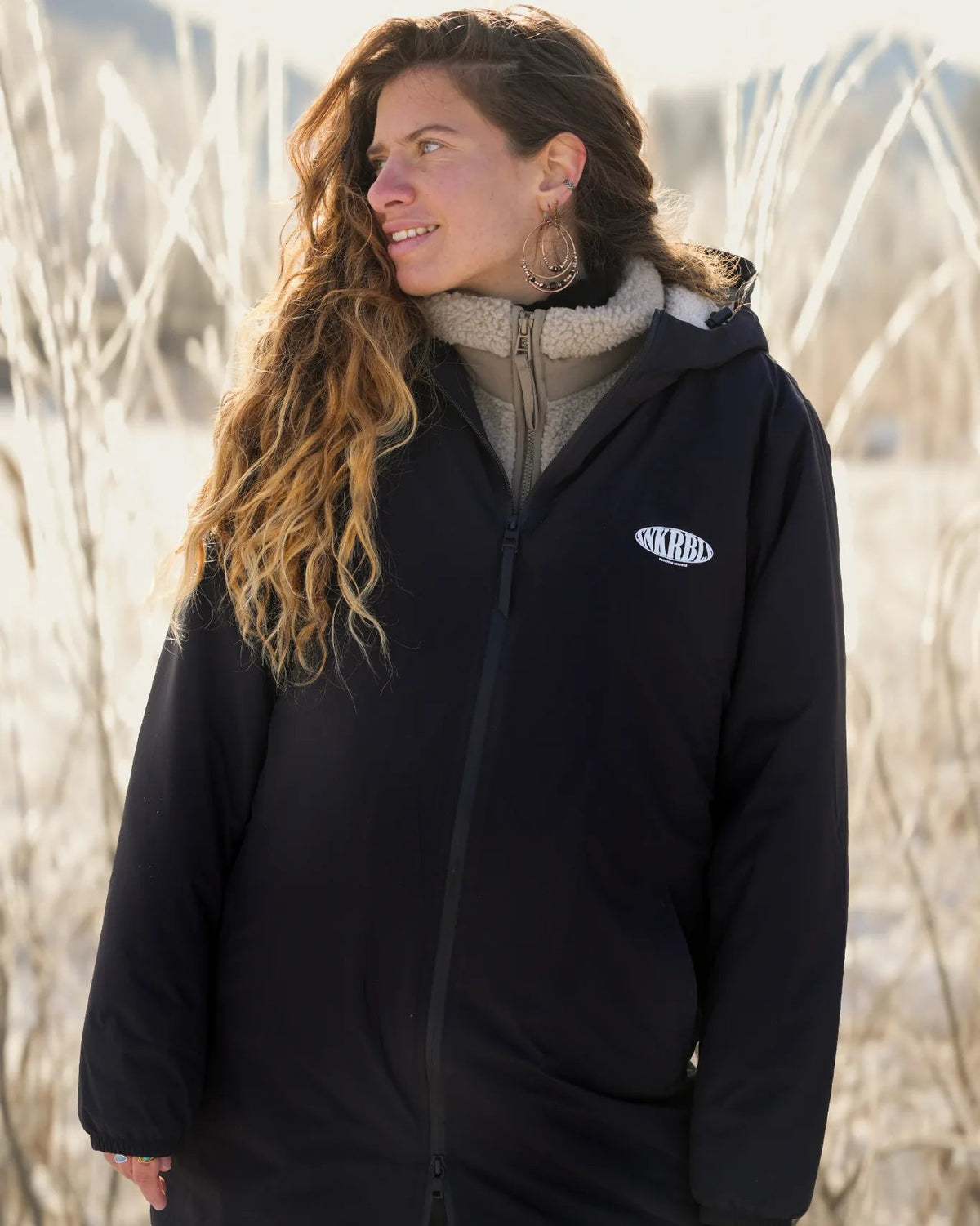 Frau trägt schwarze Rebels Waterproof Sherpa Jacke von The Sunkissed Rebels im Winter Outdoor Portrait