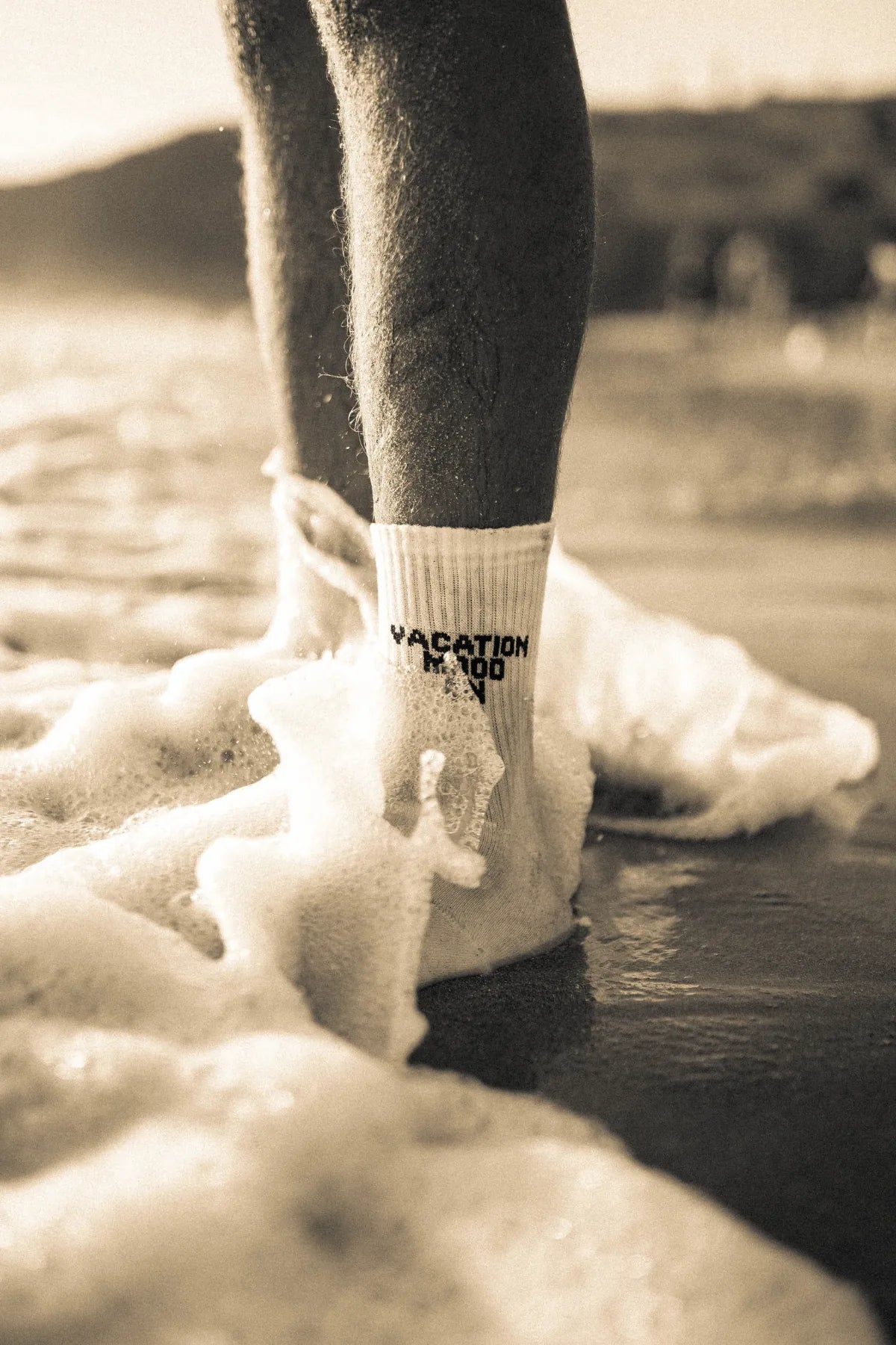Künstlerischer Sepia-Moment am Strand mit weißen Vacation Mood On Tennissocken – lässiger Retro-Vibe