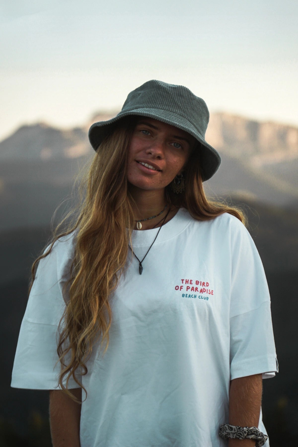 Weißes Oversized Shirt The Bird of Paradise von The Sunkissed Rebels – frontal mit grünem Bucket Hat