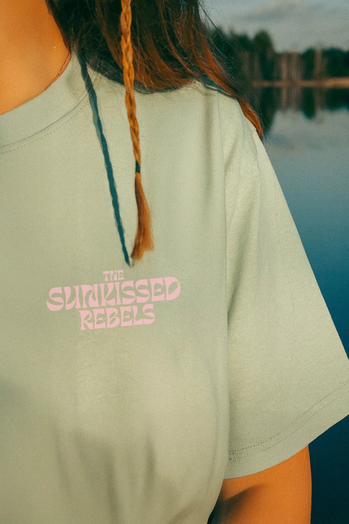 Detailaufnahme des pinken Frontlogos von The Sunkissed Rebels auf mintgrünem Shirt