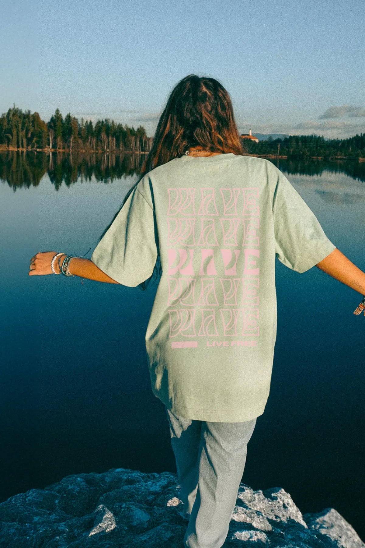 Rückseite des mintgrünen Shirts vor ruhiger Seenlandschaft mit Waldkulisse