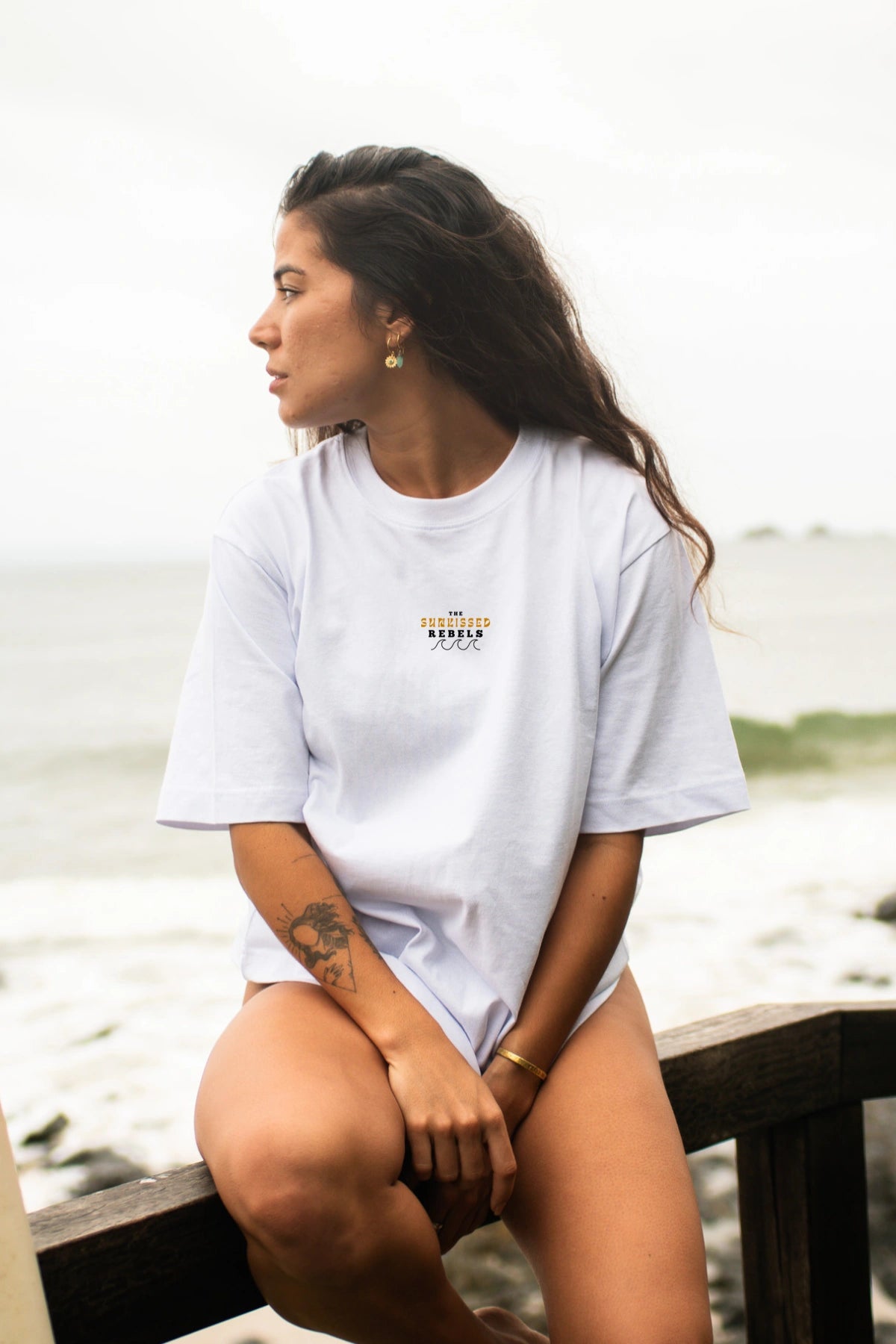 Seitliche Ansicht vom weißen Oversized T-Shirt Paradise & Sunset von The Sunkissed Rebels am Wasser