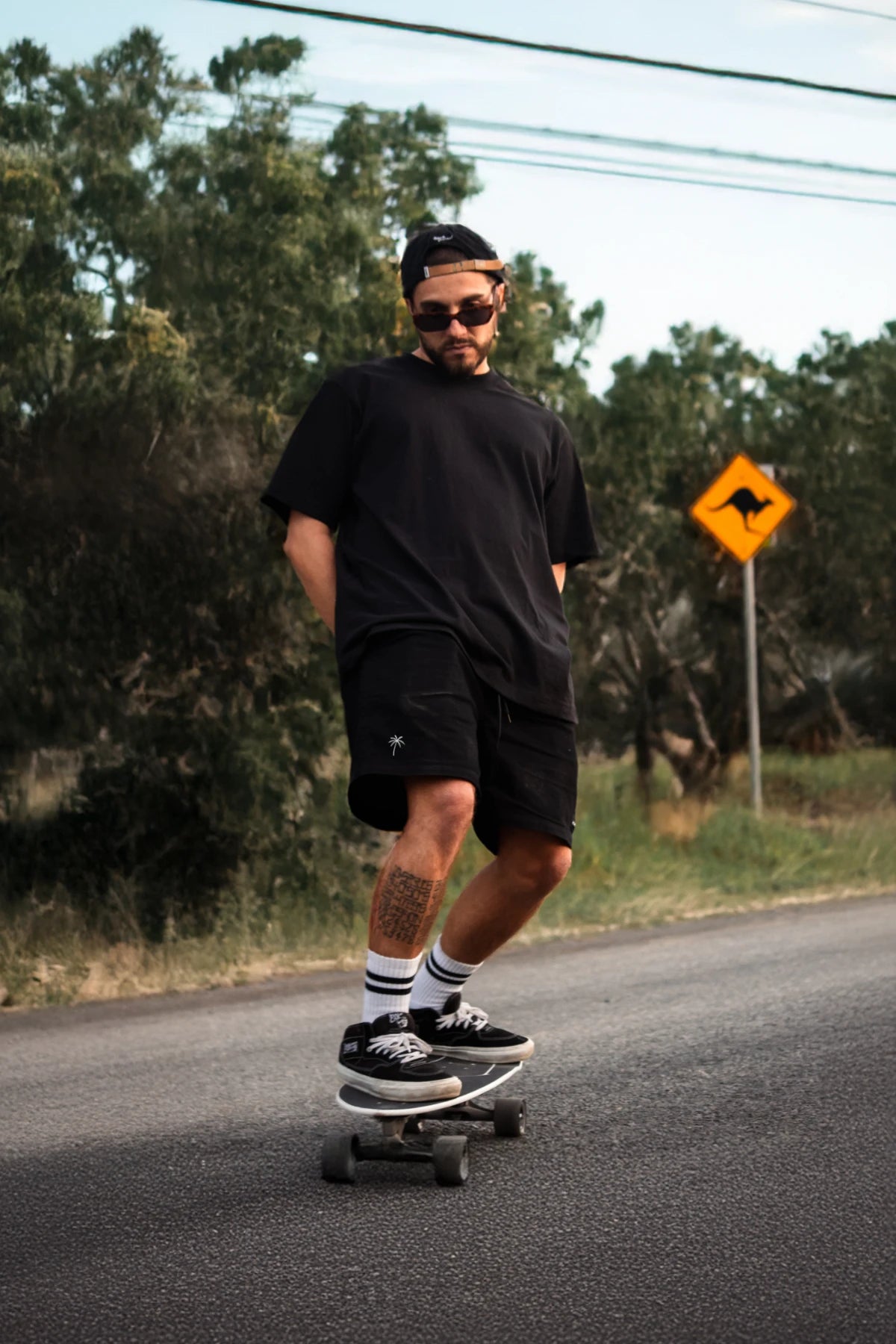 Skater im schwarzen Oversize-T-Shirt fährt Longboard bei Tageslicht