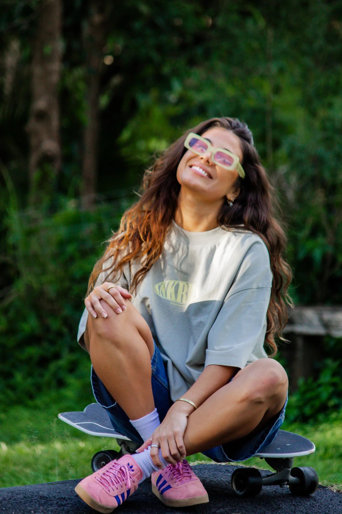 Model im SNKRBLS Oversized Shirt Stone lächelt zufrieden im Naturumfeld