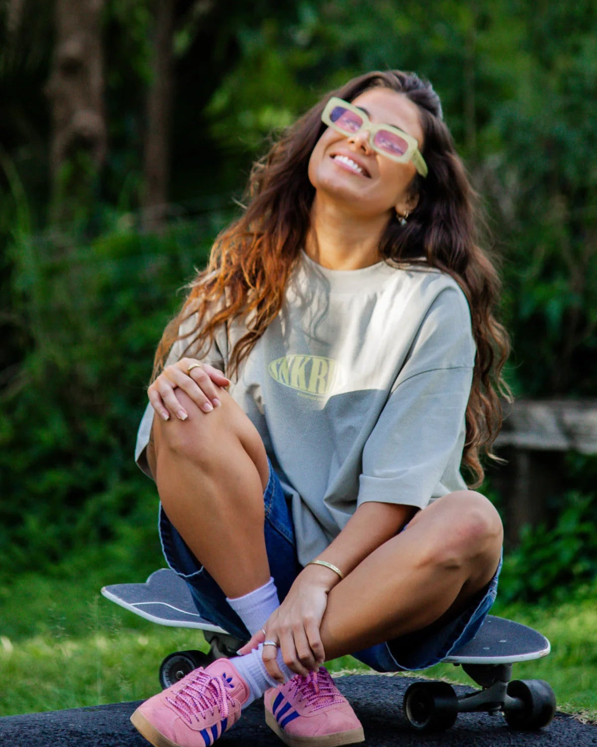 Model im SNKRBLS Oversized Shirt Stone lächelt zufrieden im Naturumfeld
