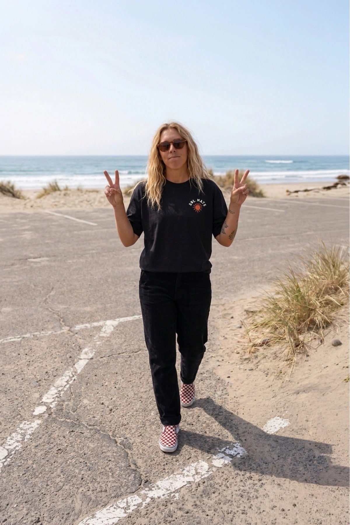 Frontansicht des schwarzen Sol Mate Oversized T-Shirts von The Sunkissed Rebels am Strand mit kleinem Brustprint