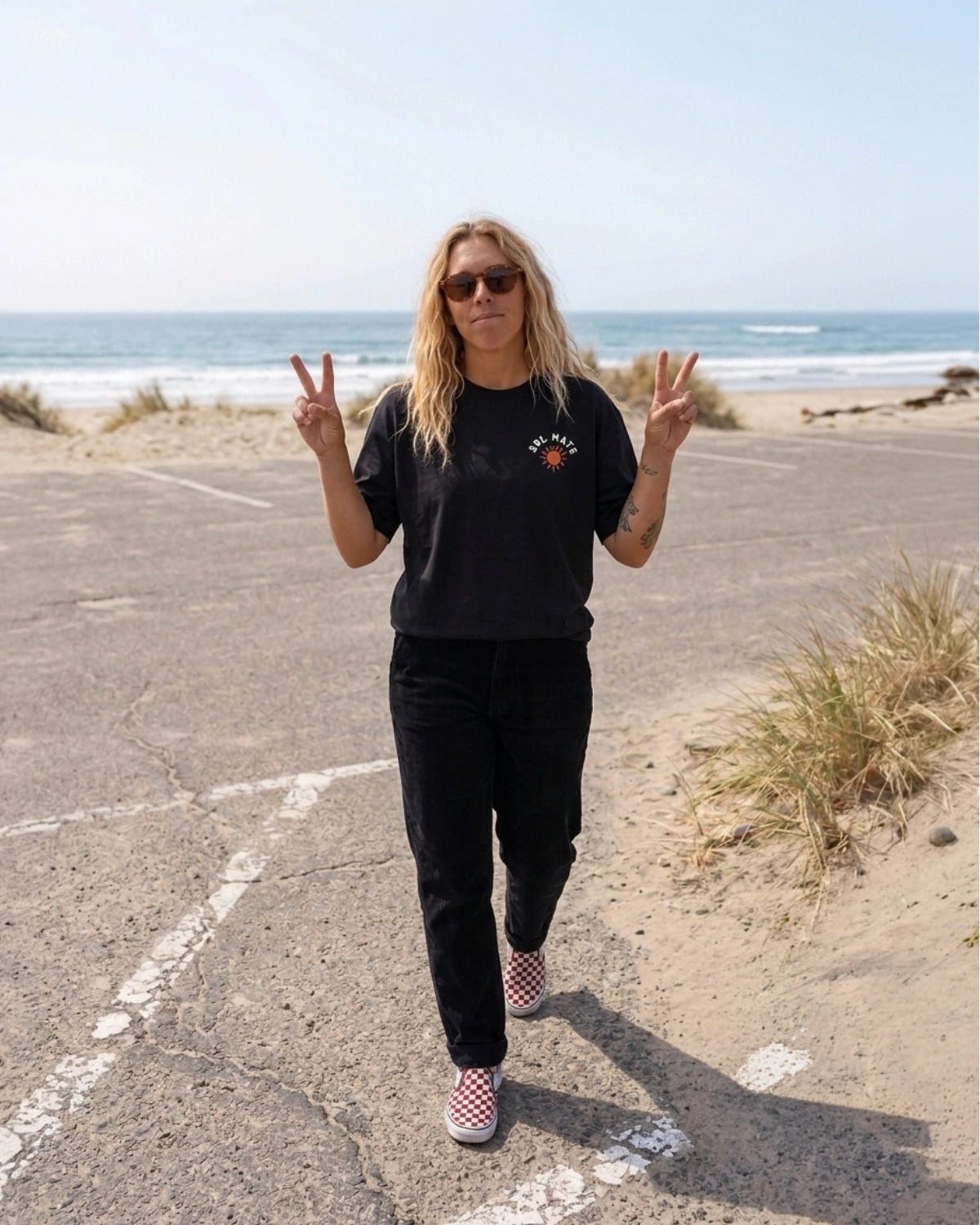 Frontansicht des schwarzen Sol Mate Oversized T-Shirts von The Sunkissed Rebels am Strand mit kleinem Brustprint