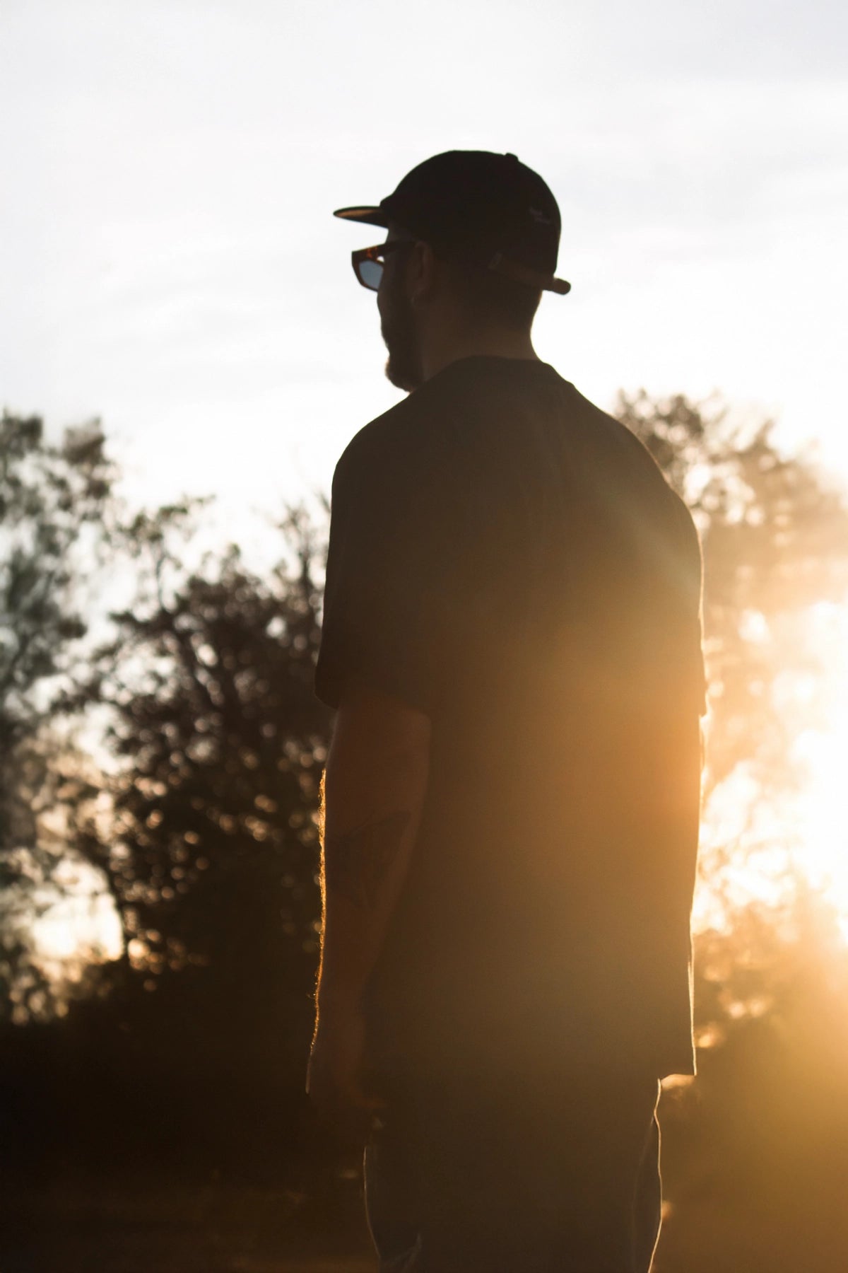 Streetwear-Skater mit Cap auf einsamer Landstraße bei Sonnenuntergang