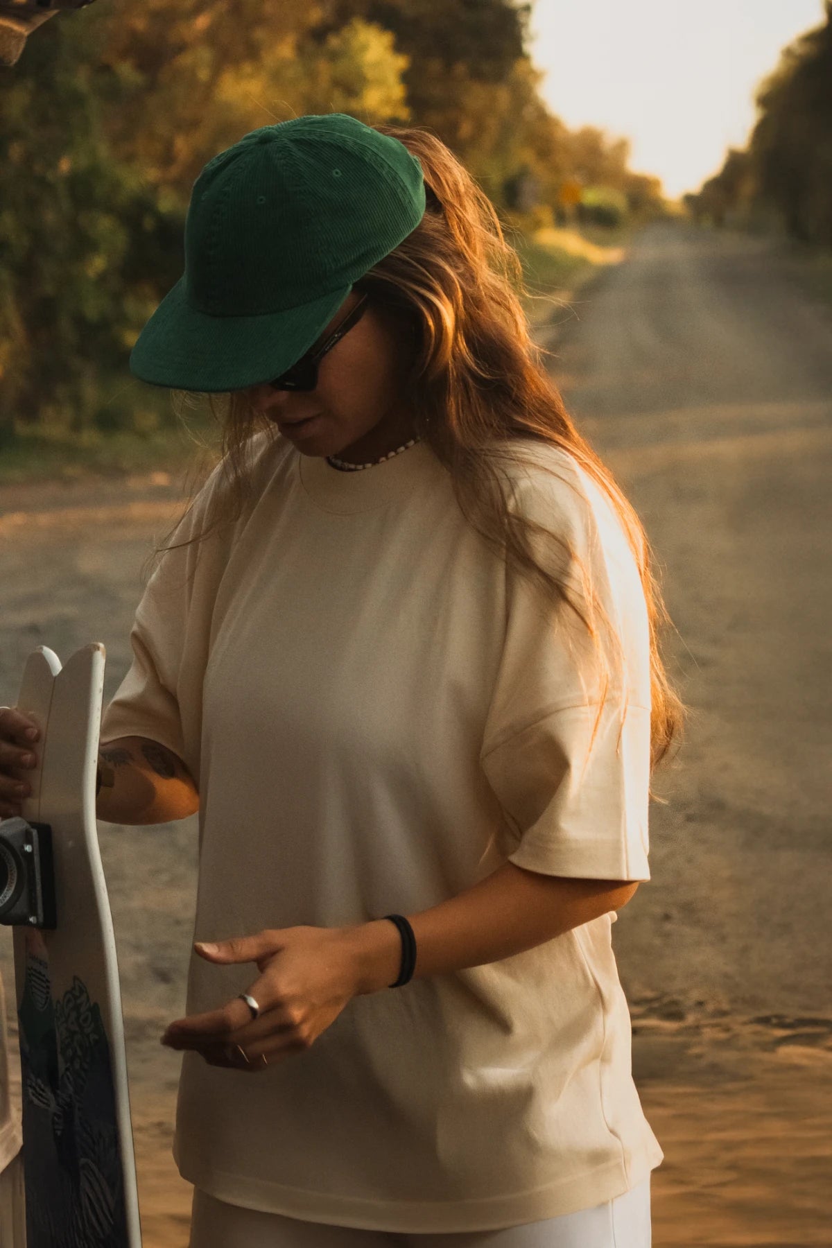 Skaterin mit Streetwear-Look und naturfarbenem T-Shirt in der Abendsonne