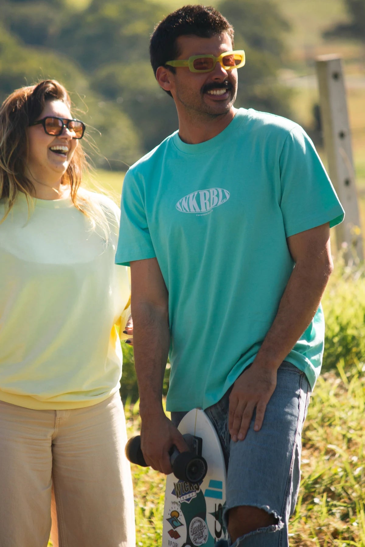Zwei Freunde mit Skateboards in der Sonne – das SNKRBLS T-Shirt in Pool Blue bringt sommerliche Skater-Vibes in Szene