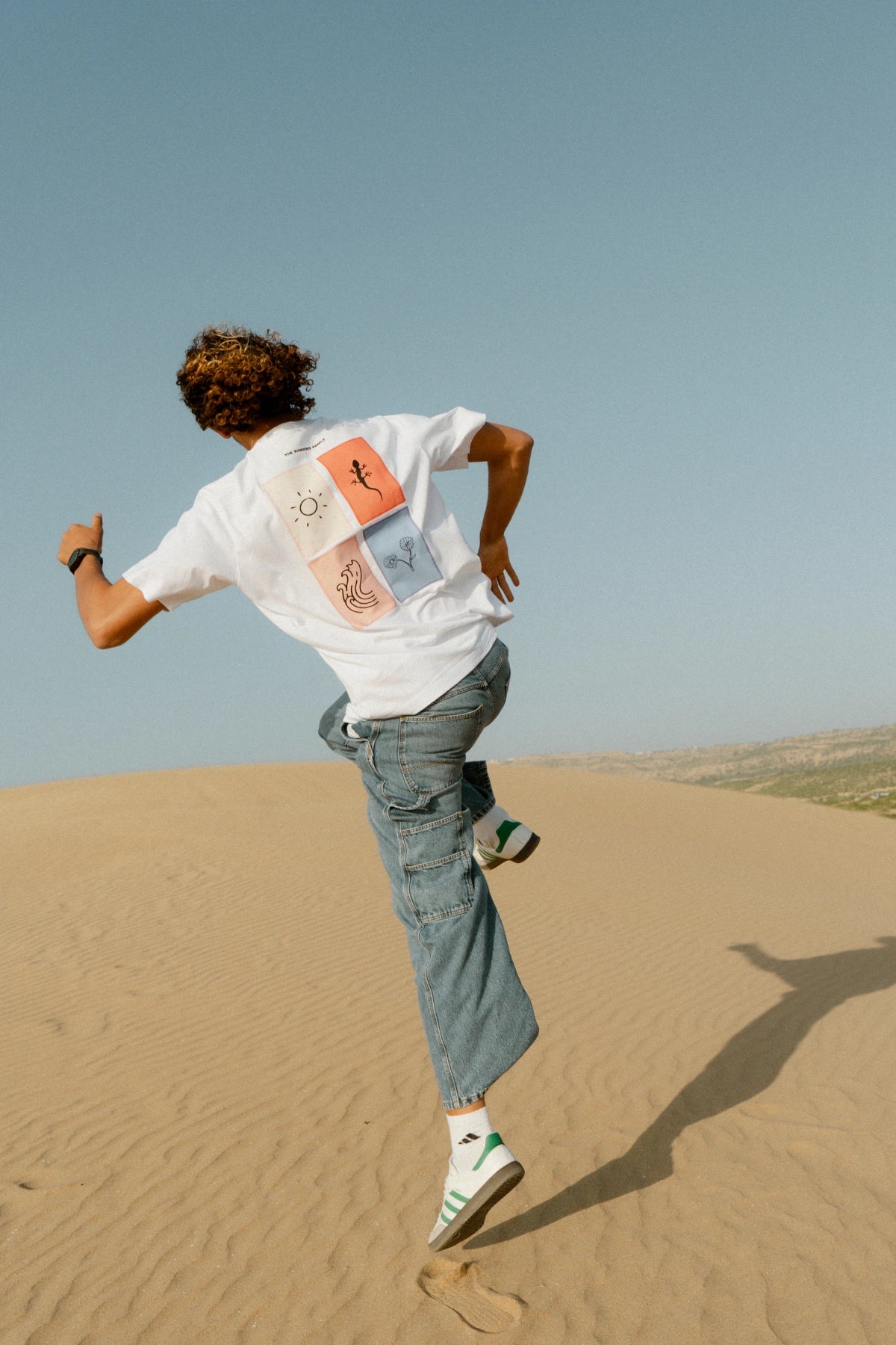 The Rebel Elements T-Shirt White Backprint getragen Bewegung Sanddünen Streetwear dynamisch