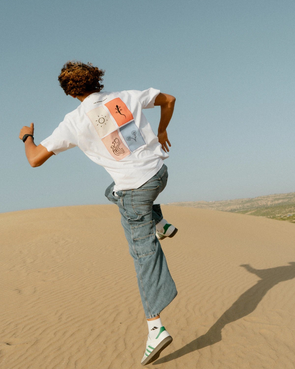 The Rebel Elements T-Shirt White Backprint getragen Bewegung Sanddünen Streetwear dynamisch