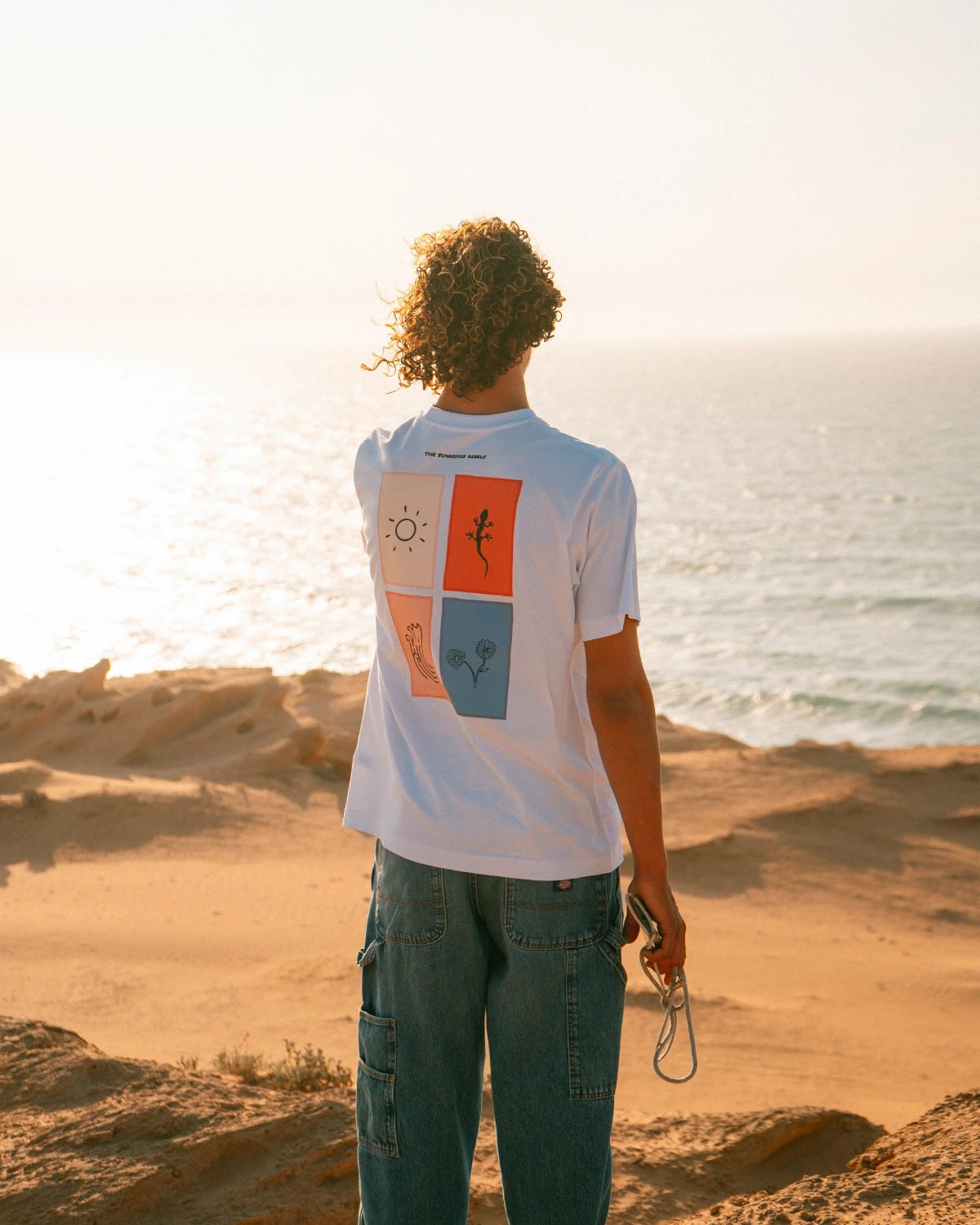 The Rebel Elements T-Shirt White Backprint getragen am Meer Sonnenuntergang Lifestyle Sommer