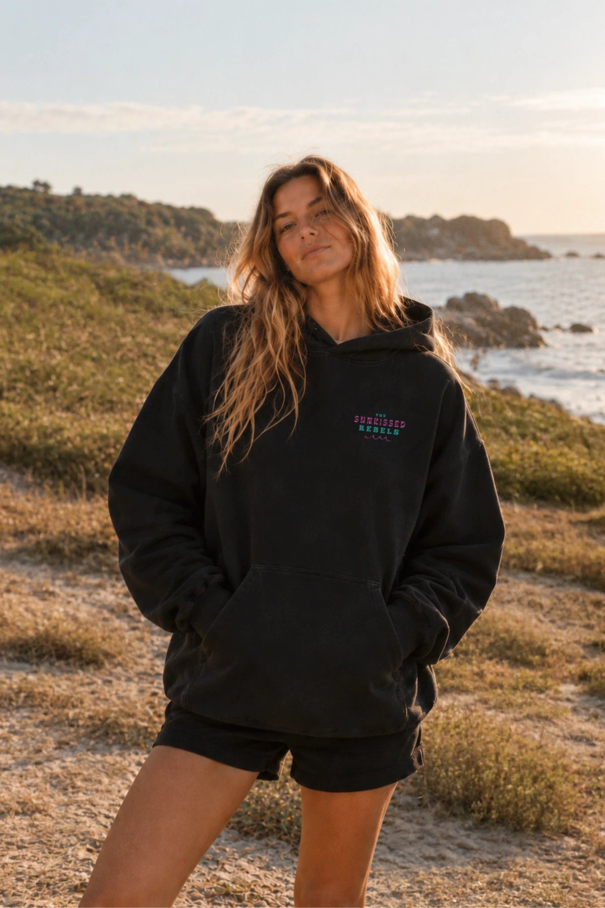 Frontansicht des Vacation Vibes Oversized Hoodies in Schwarz mit kleinem Brustprint an der Küste – The Sunkissed Rebels