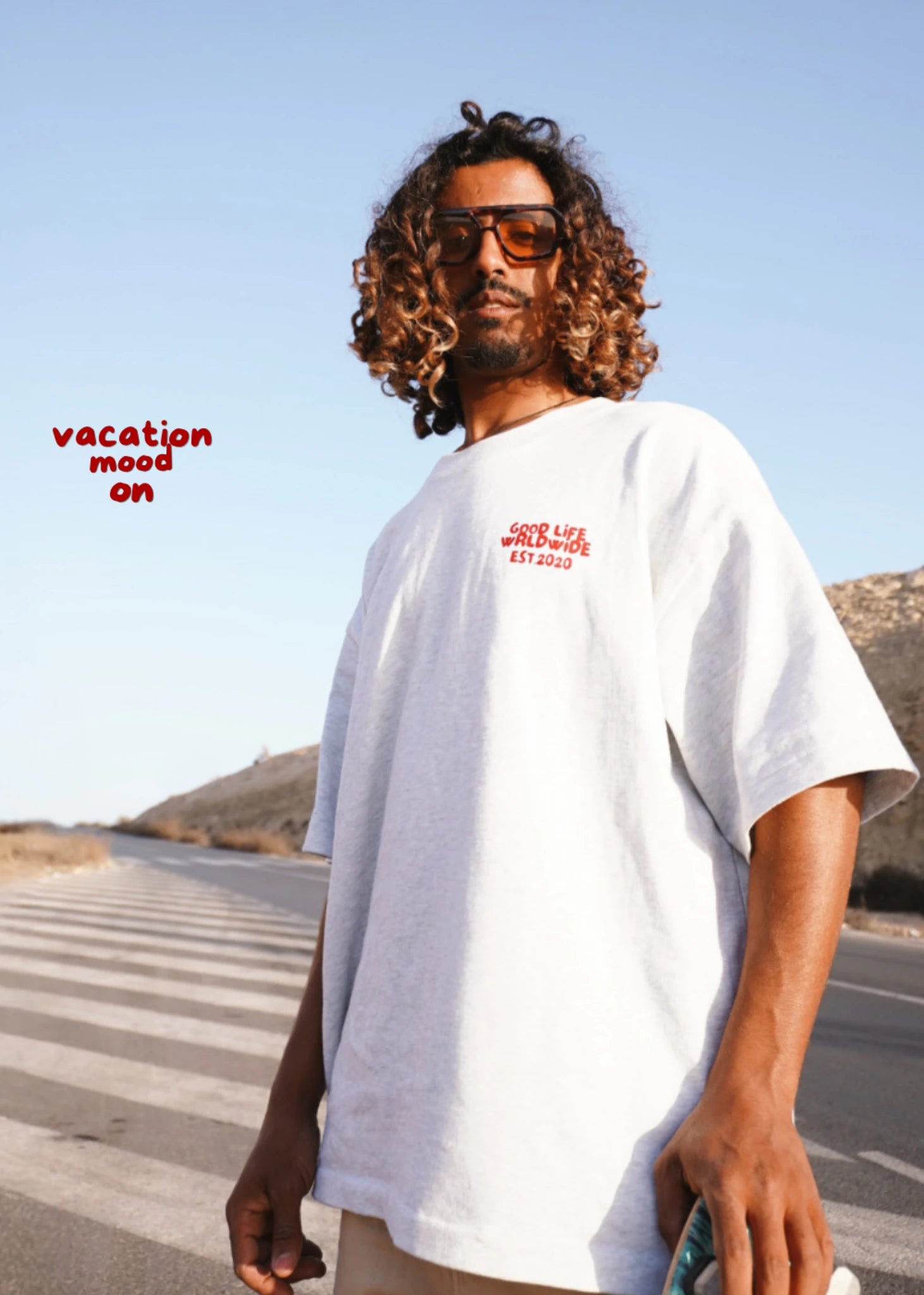 Model mit weißem T-Shirt und Sonnenbrille auf Straße mit Palmen – Summer Vacation Mood Outfit