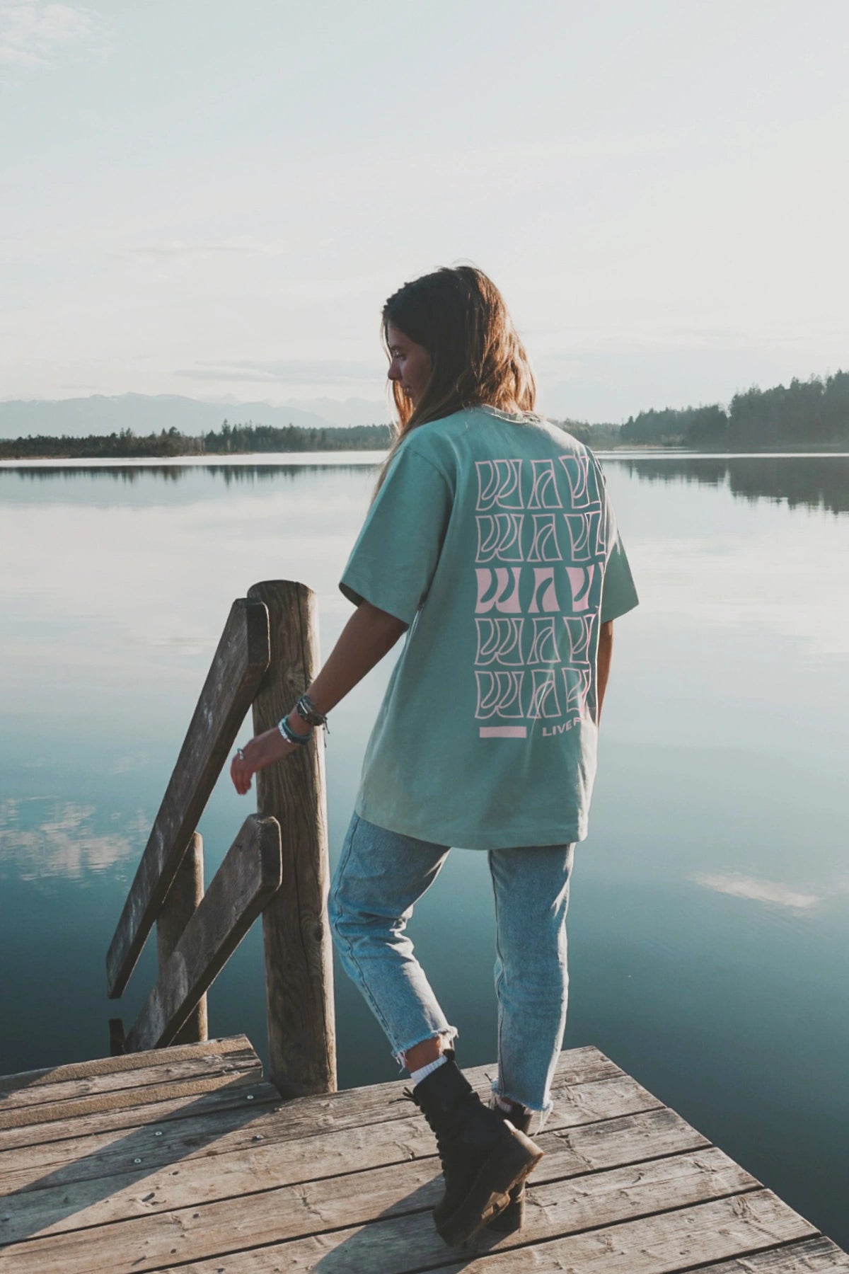 Lifestyle-Motiv mit Oversize-Live-Free-Shirt in Grün auf Steg vor Bergsee
