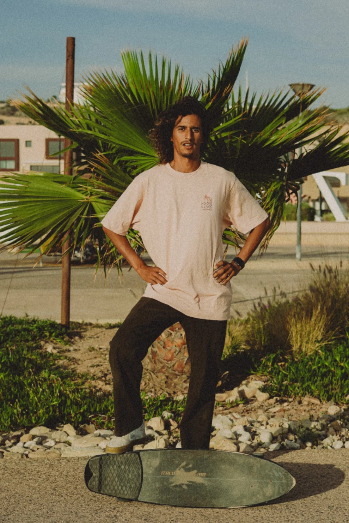 Mann vor Palme trägt das Coral T-Shirt mit kleinem Frontprint von The Sunkissed Rebels