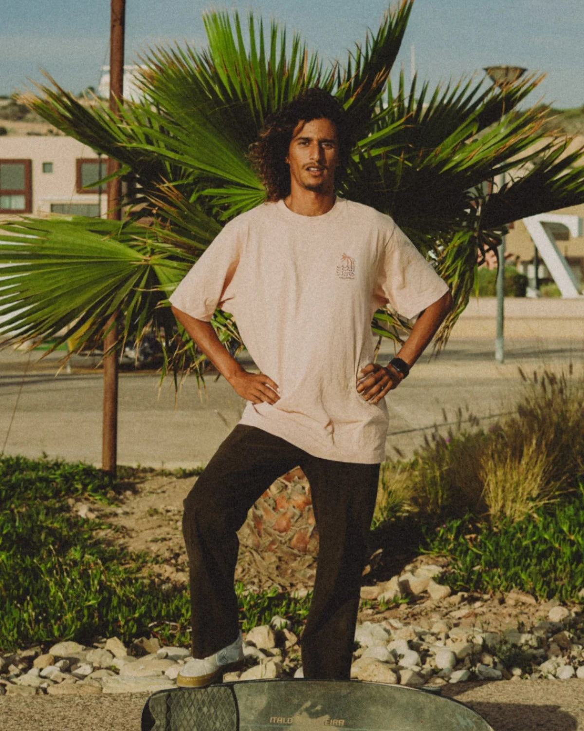 Mann vor Palme trägt das Coral T-Shirt mit kleinem Frontprint von The Sunkissed Rebels