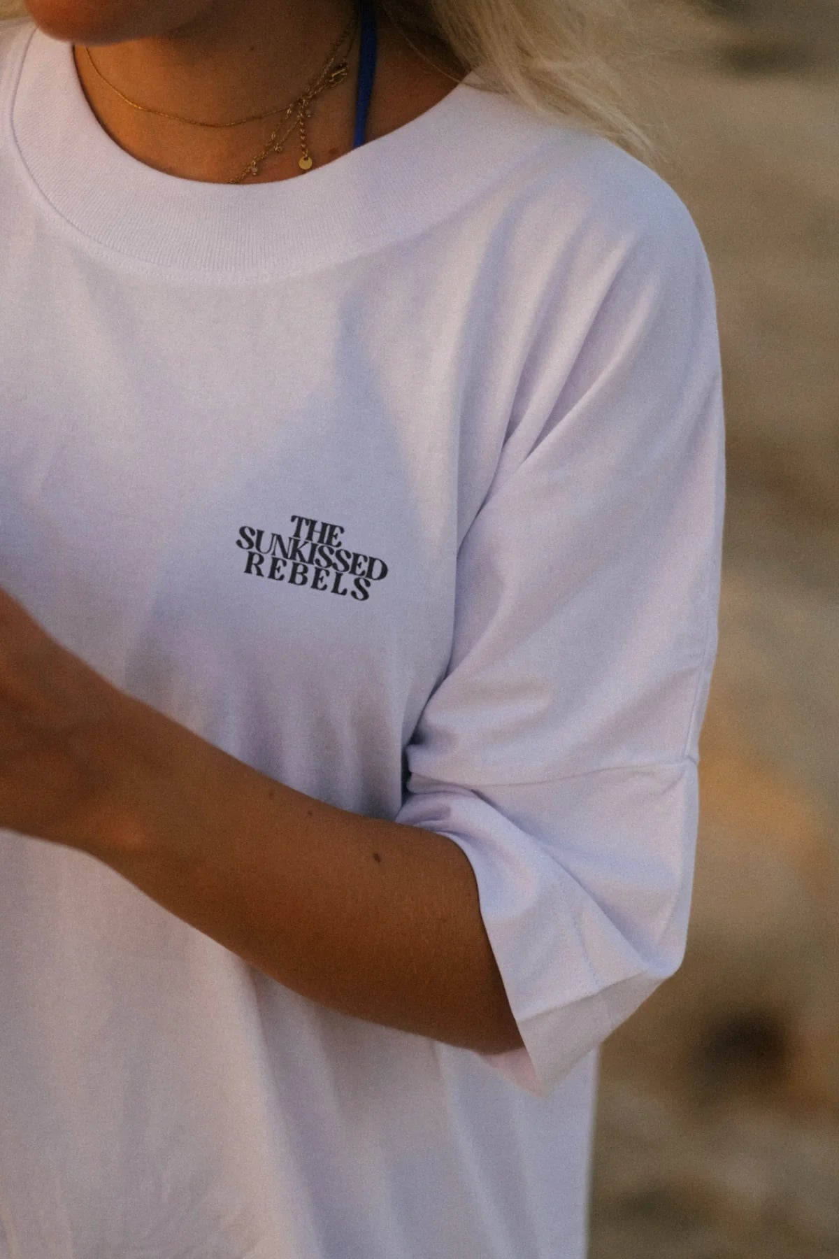 Nahaufnahme vom weißen Oversized T-Shirt mit THE SUNKISSED REBELS Logo