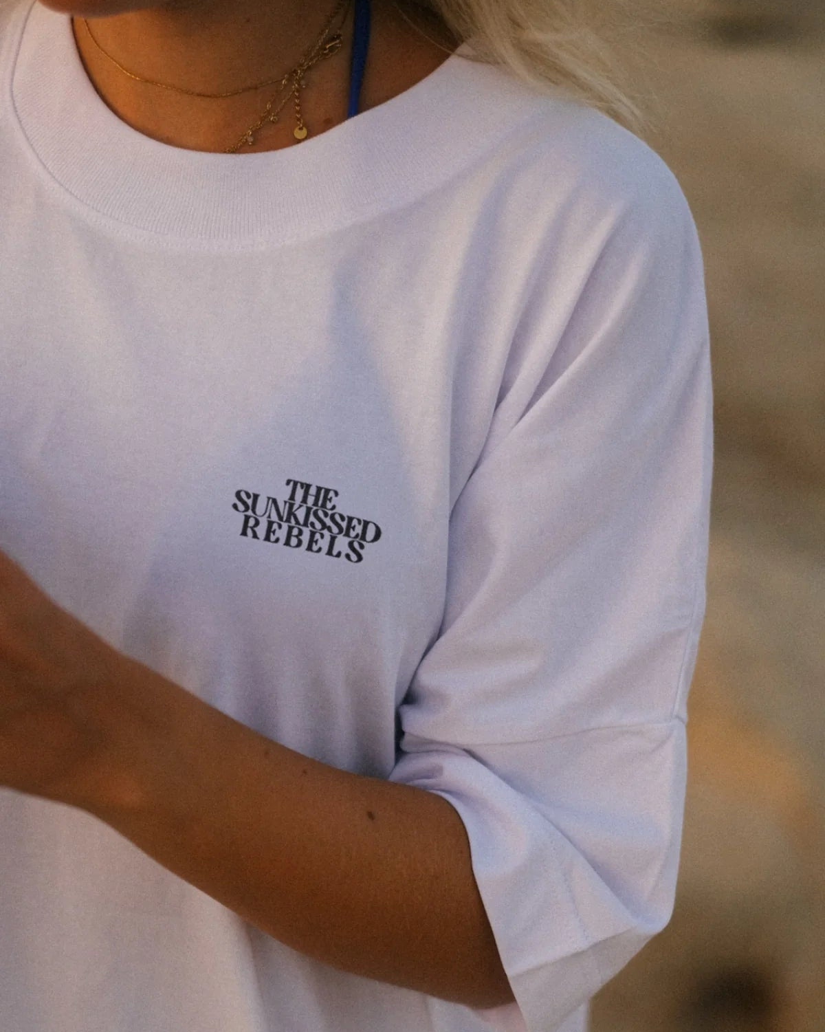 Nahaufnahme vom weißen Oversized T-Shirt mit THE SUNKISSED REBELS Logo