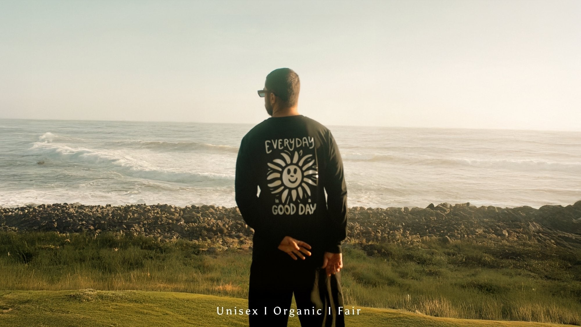 Mann im schwarzen Longsleeve von The sunkissed Rbeels steht am strand