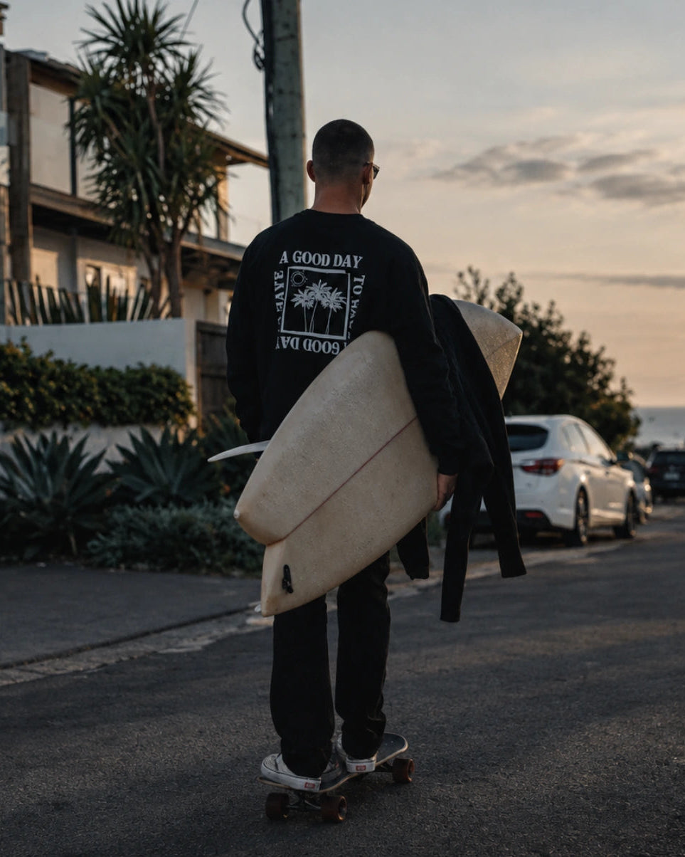 Mann trägt A Good Day Sweater Black von The Sunkissed Rebels an Küstenlandschaft