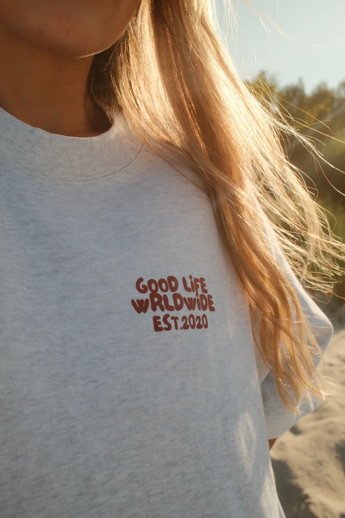 Detailansicht des roten Good Life Worldwide Est. 2020 Brustprints auf schwerem Cool Grey Baumwollstoff von The Sunkissed Rebels.