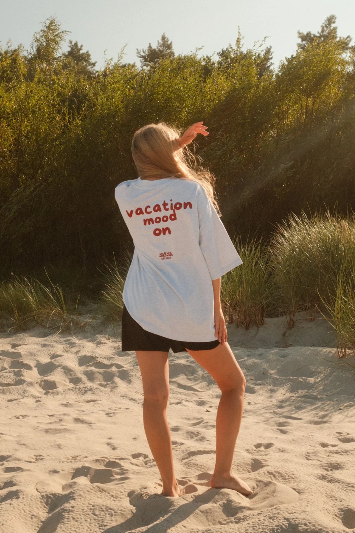 Entspannter Strandlook im grauen Goodlife Heavyweight Shirt von The Sunkissed Rebels im sonnigen Gegenlicht.