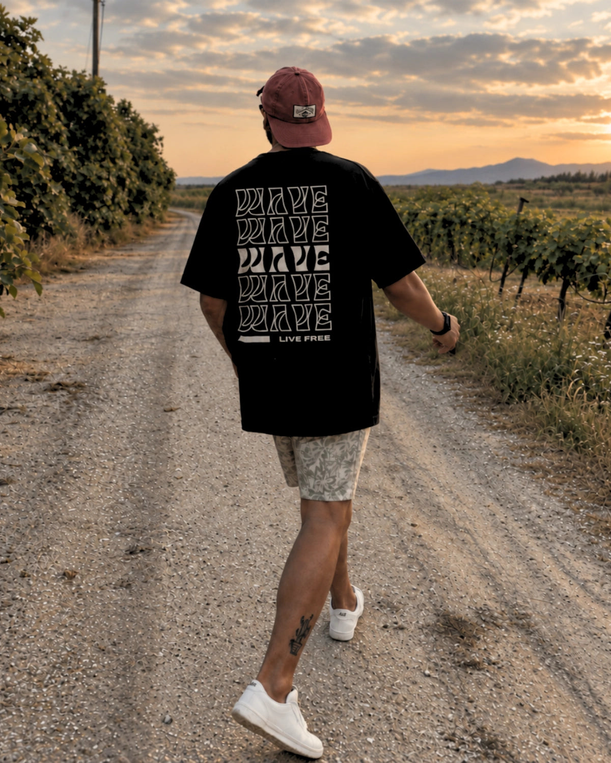 Schwarzes Live Free Oversized T-Shirt von The Sunkissed Rebels mit großem Backprint auf einem Weg zwischen Weinbergen
