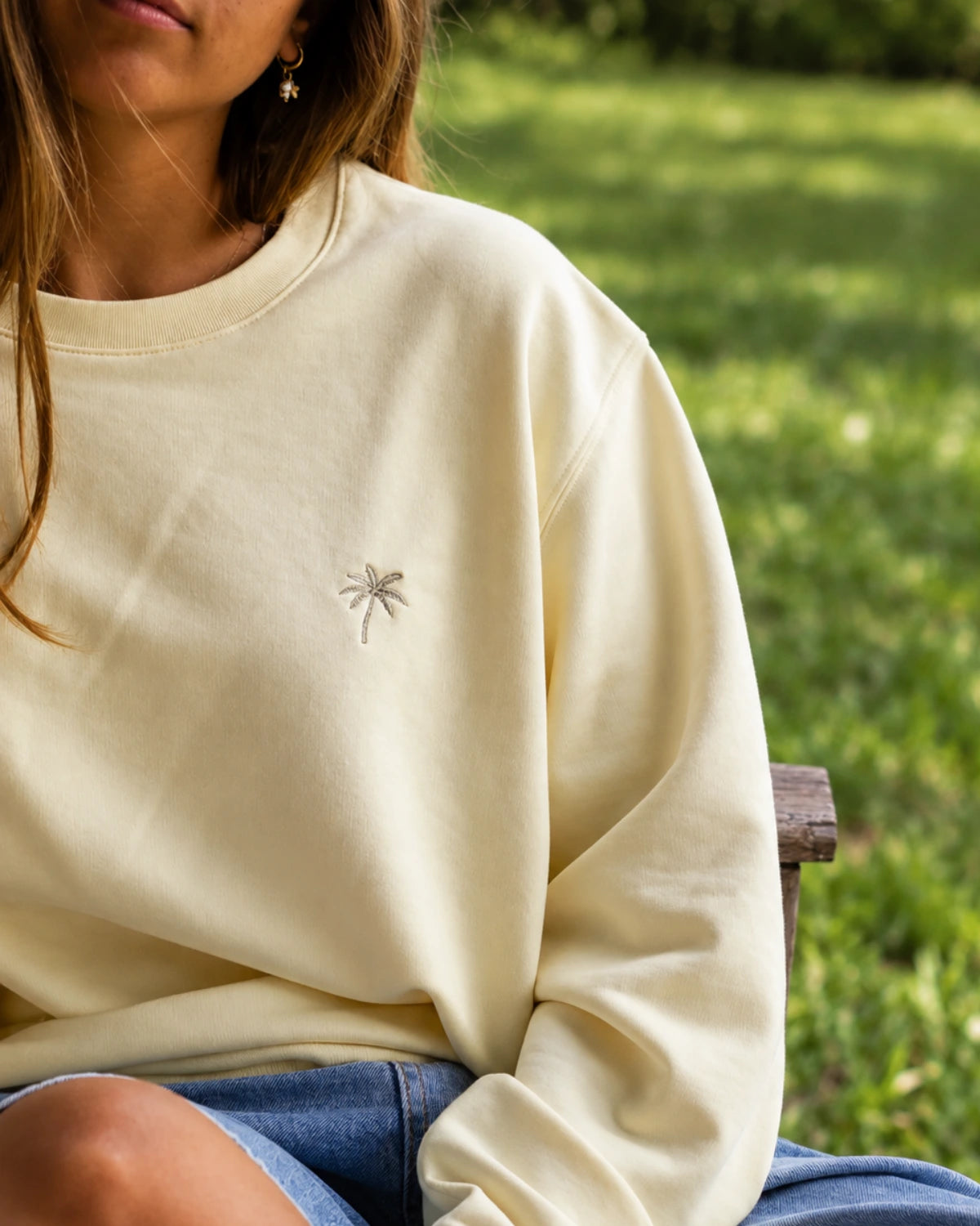 Detailaufnahme des Palm Tree Sweaters in Butter mit kleinem Palmenstick auf der Brust