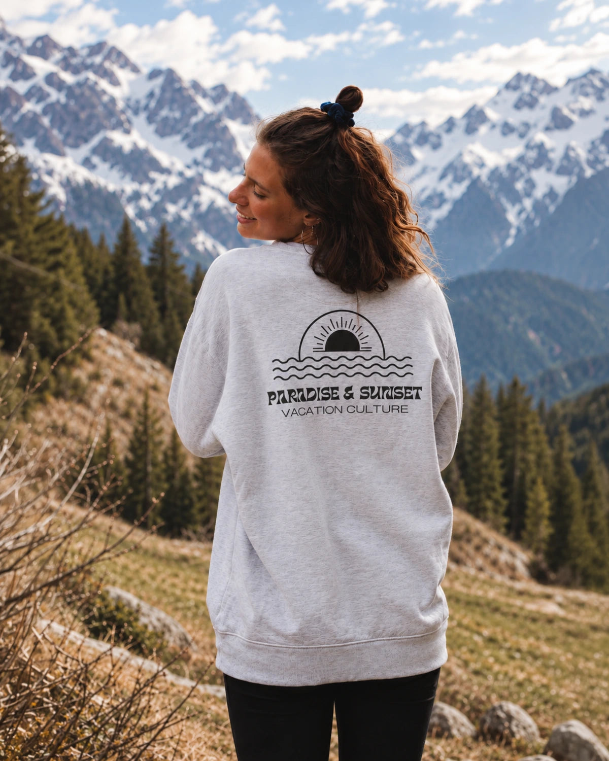 Rückansicht des Paradise & Sunset Sweaters in Cool Grey mit großem Paradise & Sunset Rückenprint vor Bergkulisse