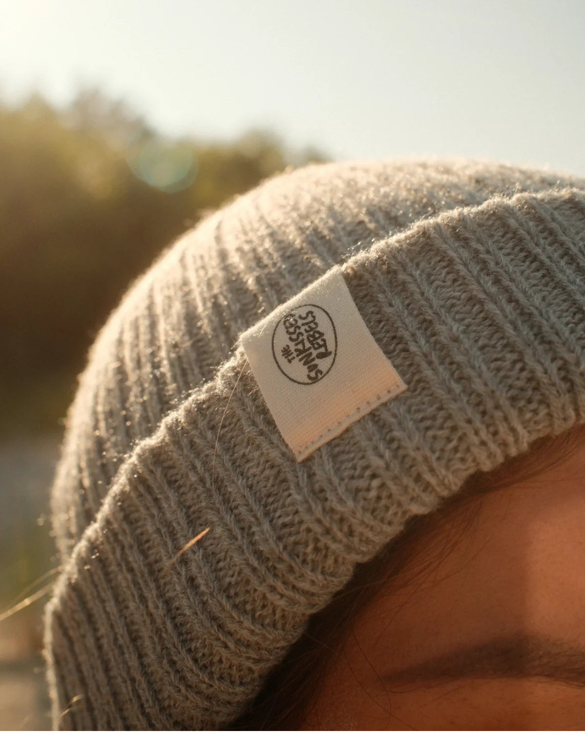 Detailaufnahme der grauen Wollmütze Rebels Knit Beanie Stormy Grey von The Sunkissed Rebels mit gewebtem Logo-Label.