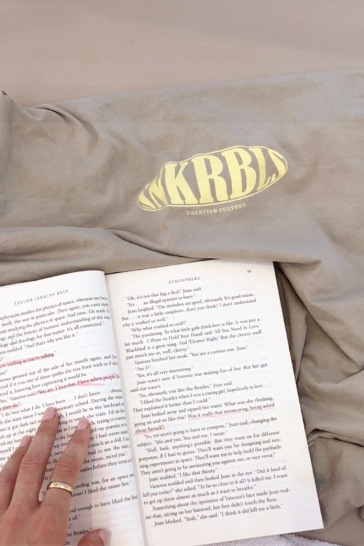 T-Shirt in Beige mit KRBL-Print neben einem Buch – Cozy Vibes & Vacation Mood