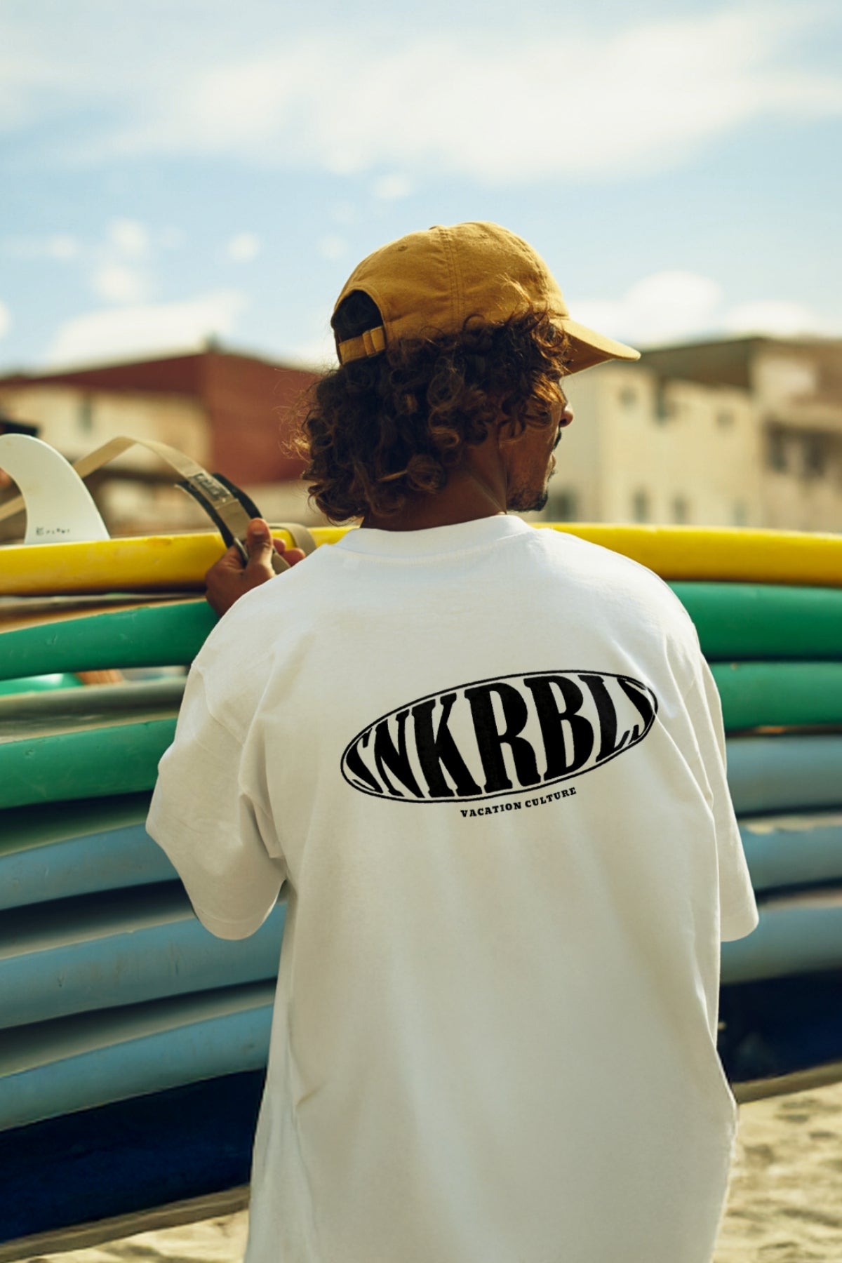 Surfer befästigt Surfbretter am Strand tärgt Oversized T-shirt in Weiss