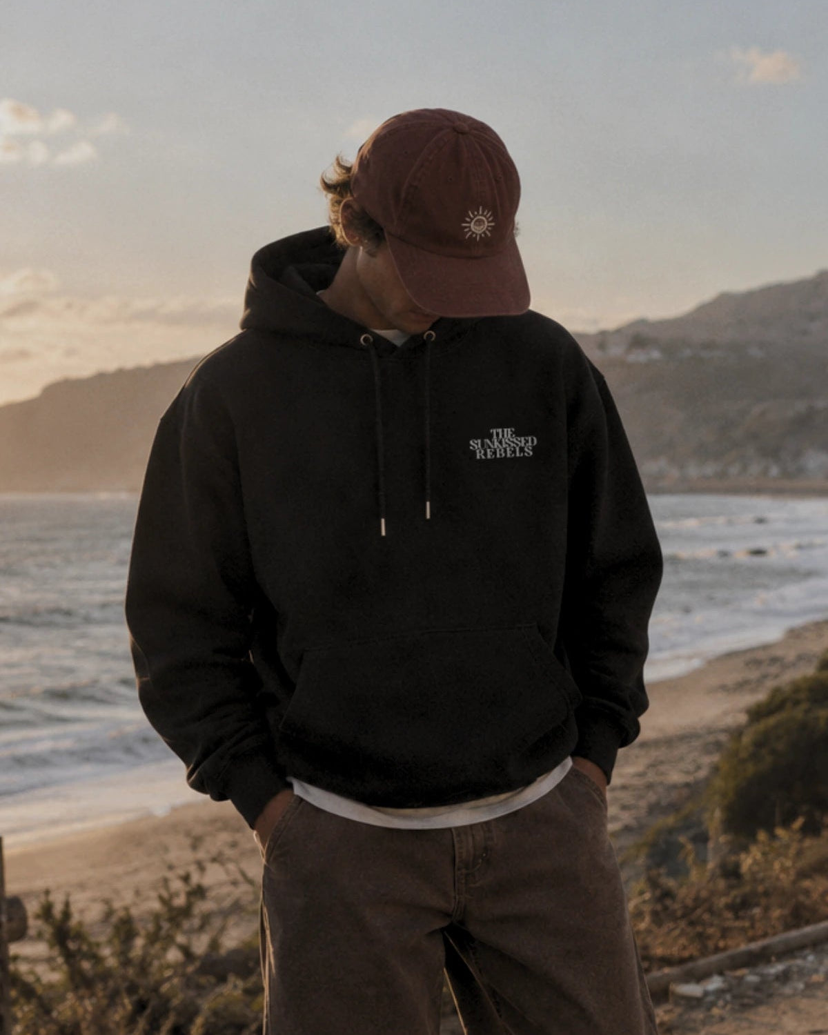 Entspannter Fit des Vacation Mood On Hoodie in Schwarz kombiniert mit brauner Hose 